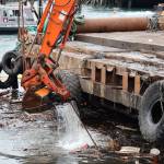 An excavator on a barge scoops floating debris near the shore of Gastineau Channel on Monday morning. The effort was a part of the recovery process of a 107-foot tugboat that sank at a dock south of the cruise ship docks in late December. (Clarise Larson / Juneau Empire)