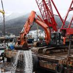 An excavator on a barge scoops floating debris near the shore of Gastineau Channel on Monday morning. The effort was a part of the recovery process of a 107-foot tugboat that sank at a dock south of the cruise ship docks in late December. (Clarise Larson / Juneau Empire)