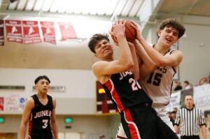 Juneau's Orion Dybdahl (20) forces a jump ball with Kayhi's Jared Rhoads (15) during Juneau's 71-52 loss to Kayhi on Friday at the Clarke Cochrane Gymnasium. (Christopher Mullen / Ketchikan Daily News)
