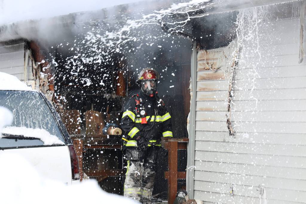 A Capital City Fire/Rescue firefighter moves to extinguish a trailer fire Friday morning. The cause of the fire is believed to be caused by an electric toaster, officials say. (Clarise Larson / Juneau Empire)