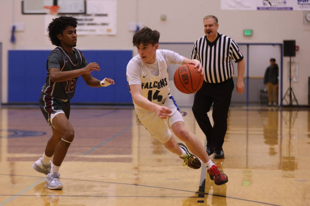 TMHS junior Samuel Lockhart (14)dribbles toward the hoop while defended by Kayhi senior JJ Parker (13). (Ben Hohenstatt / Juneau Empire)