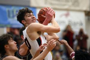 JDHS senior Orion Dybdahl rips down a board in a close contest against Ketchikan. The game took 36 minutes of gametime to resovle and ended 72-64 in Kayhi's favor. The Crimson Bears and Kings will play for the Region V 4A title at 8:15 p.m. Saturday at Thunder Mountain High School. (Ben Hohenstatt / Juneau Empire)