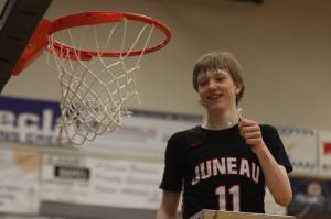JDHS junior Sean Oliver (11) holds string from the championship net after a win against Ketchikan High School, making the Crimson Bears this years Region V 4A Tournament champs. Oliver finished the game with 30 points, six 3-pointers and a fourth-quarter slam dunk. (Jonson Kuhn / Juneau Empire)