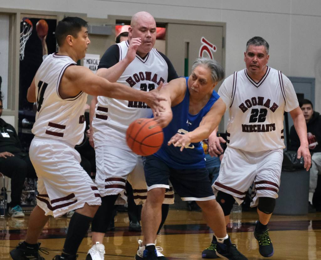 Hoonahs Joe Cornell (14), Andy Gray (23) and Albert Hinchman (22) defend Kakes Ray Cornell (30) during Masters Bracket action at the Juneau Lions Club 74th Annual Gold Medal Basketball Tournament, Sunday, March 19, at the Juneau-Douglas High School: Yadaa.at Kalé gymnasium. (Klas Stolpe / For the Juneau Empire)