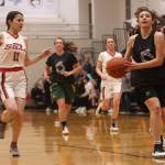 Prince of Wales Michaela Demmert makes her way down the court for a layup with Hoonahs Ronnie Roberts (11) in pursuit. (Ben Hohenstatt / Juneau Empire)