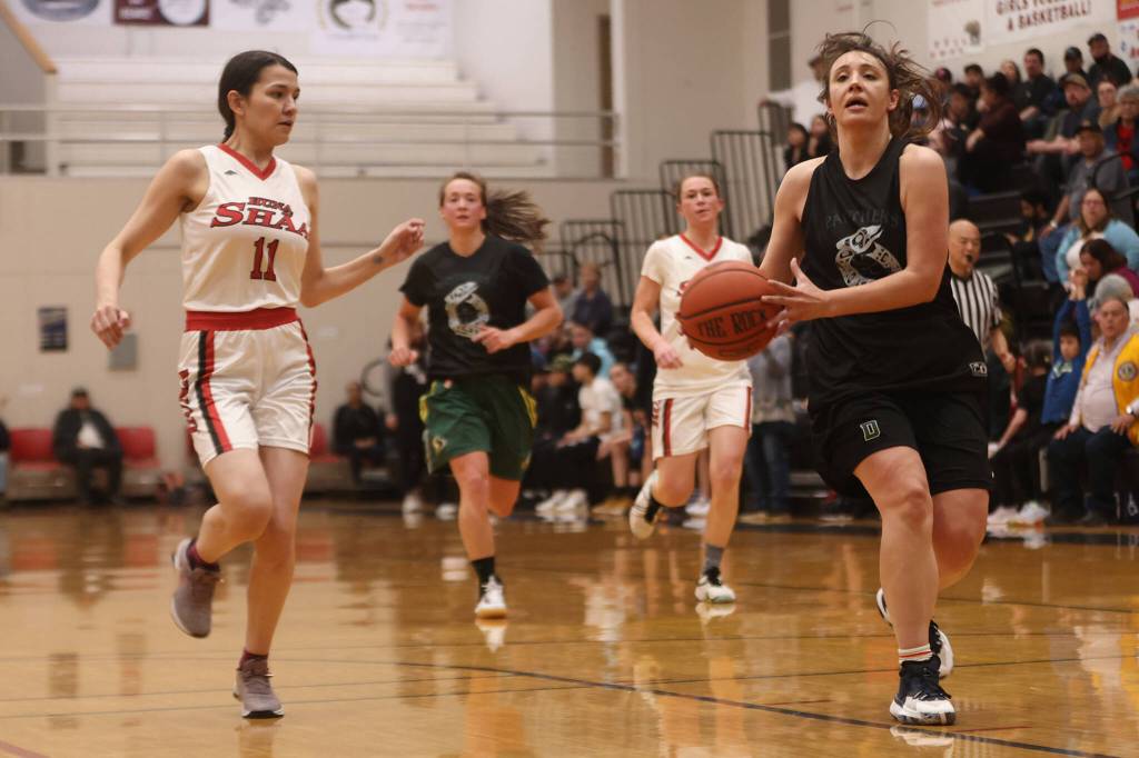 Prince of Wales Michaela Demmert makes her way down the court for a layup with Hoonahs Ronnie Roberts (11) in pursuit. (Ben Hohenstatt / Juneau Empire)