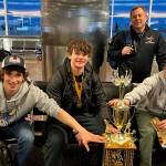 Coach Jason Kohlhase joins players, from left, Lake Bartlett, Brandon Campbell and son, Karter Kohlhase, around the teams 18-and-Under, Tier A hockey state championship trophy. Campbell ended the triple overtime marathon by ramming home a rebound off teammate Kohlhases face off shot. (Courtesy Photo / Kristin Bartlett)