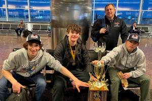 Coach Jason Kohlhase joins players, from left, Lake Bartlett, Brandon Campbell and son, Karter Kohlhase, around the teams 18-and-Under, Tier A hockey state championship trophy. Campbell ended the triple overtime marathon by ramming home a rebound off teammate Kohlhases face off shot. (Courtesy Photo / Kristin Bartlett)
