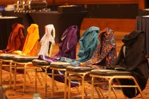Kuspuks of varying colors displayed at a tribal consultation meeting in Anchorage on Sept. 21 represent Indigenous victims of violence. From left, the colors are red for Missing and Murdered Indigenous Women, orange for victims of boarding schools, the baby kuspuk for children who will never be born, purple for victims of domestic violence, turquoise for victims of sexual assault, multicolor for LGBTQ victims and black for men who are victims. The kuspuks were arrayed at the Justice Department's annual tribal consultation conference required under the Violence Against Woman Act. In testimony Wednesday to the state House Tribal Affairs Special Committee, members of a working group listed several practical steps they said could improve safety of Indigenous people. (Photo by Yereth Rosen/Alaska Beacon)