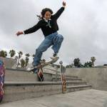 Expert skateboarder DiOrr Greenwood, an artist born and raised in the Navajo Nation in Arizona and whose work is featured on the new U.S. stamps, rides her skateboard next to her artworks in the Venice Beach neighborhood in Los Angeles Monday, March 20, 2023. On Friday, March 24, the U.S. Postal Service is debuting the Art of the Skateboard, four stamps that will be the first to pay tribute to skateboarding. The stamps underscore how prevalent skateboarding has become, especially in Indian Country, where the demand for designated skate spots has only grown in recent years. (AP Photo/Damian Dovarganes)