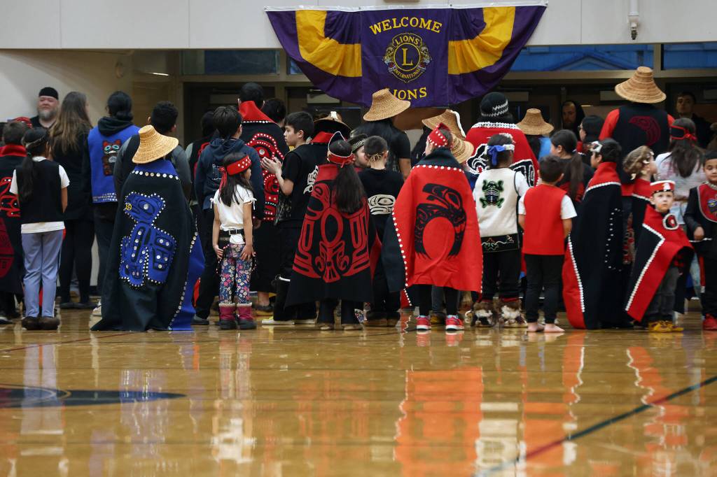 Dancers, including the Eagle Raven Dancers, Wooshji.een and students in the TCLL Program, stand in between songs Thursday evening during a performance ahead of a Gold Medal Basketball Tournament game between Juneau and Hydaburg. (Ben Hohenstatt / Juneau Empire)