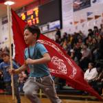 Montae Edenshaw, 8, runs with a Council of the Haida Nation flag while cheering on Hydaburg and his father, Vinny Edenshaw, during the Gold Medal B Bracket championship game on Saturday. (Ben Hohenstatt / Juneau Empire)