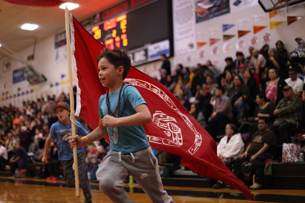 Montae Edenshaw, 8, runs with a Council of the Haida Nation flag while cheering on Hydaburg and his father, Vinny Edenshaw, during the Gold Medal B Bracket championship game on Saturday. (Ben Hohenstatt / Juneau Empire)