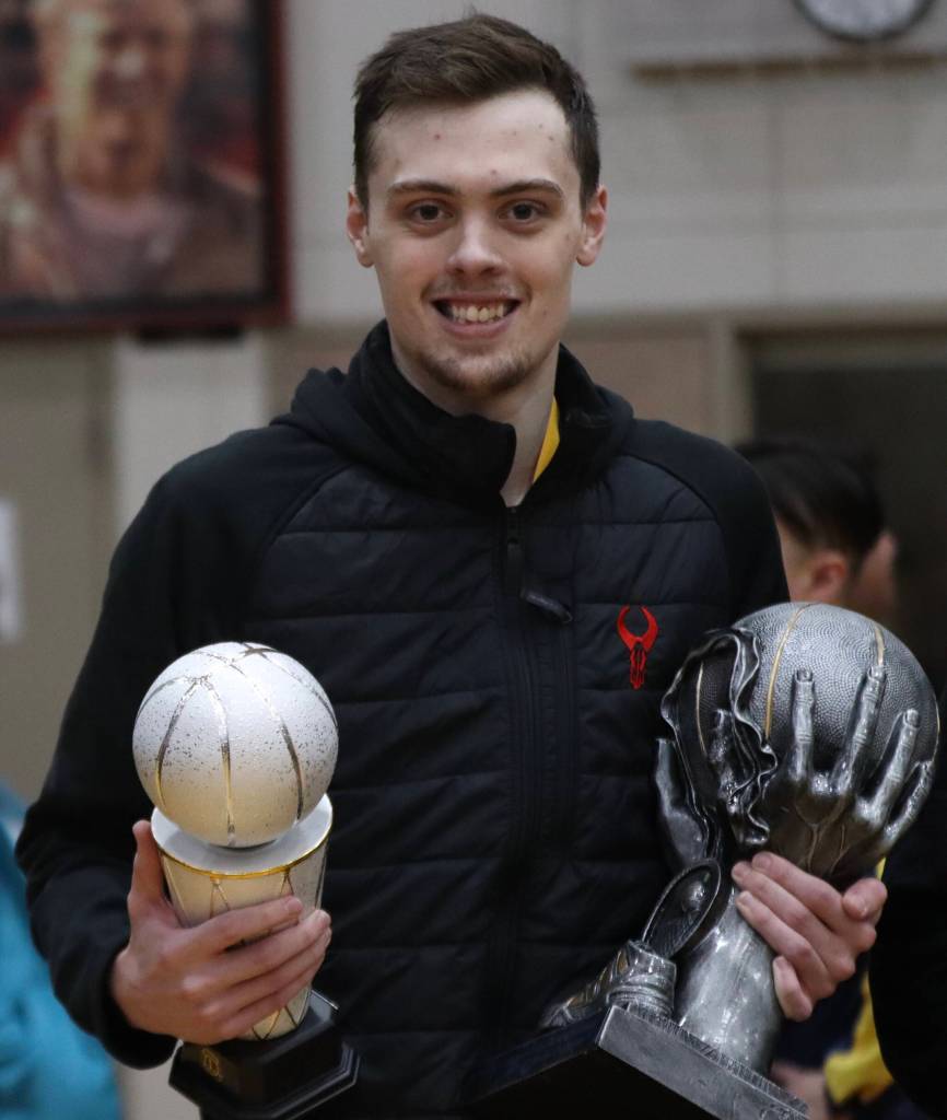 Juneaus Kaleb Tompkins poses for a photo with his MVP and B Bracket championship trophies on Saturday night after winning the B bracket championship game against Hydaburg to conclude this years Gold Medal Basketball Tournament. Tompkins finished the game with 14 points. (Jonson Kuhn / Juneau Empire)