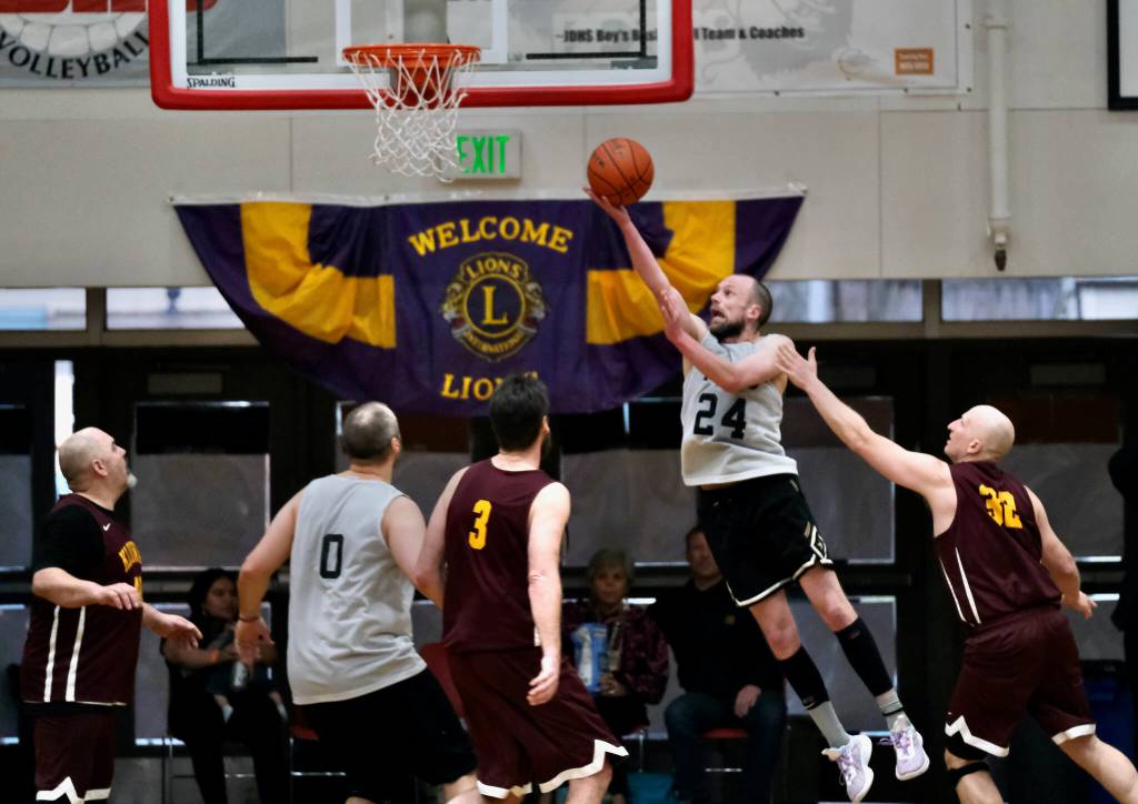 Filcoms Alex Heumann (24) scores past Klukwans Paul Carrington (3) and Brian Friske (32) during the C Bracket Championship game of the Gold Medal Basketball Tournament, Saturday, March 25, at Juneau-Douglas High School: Yadaa.at Kalé. (Klas Stolpe/For the Juneau Empire)