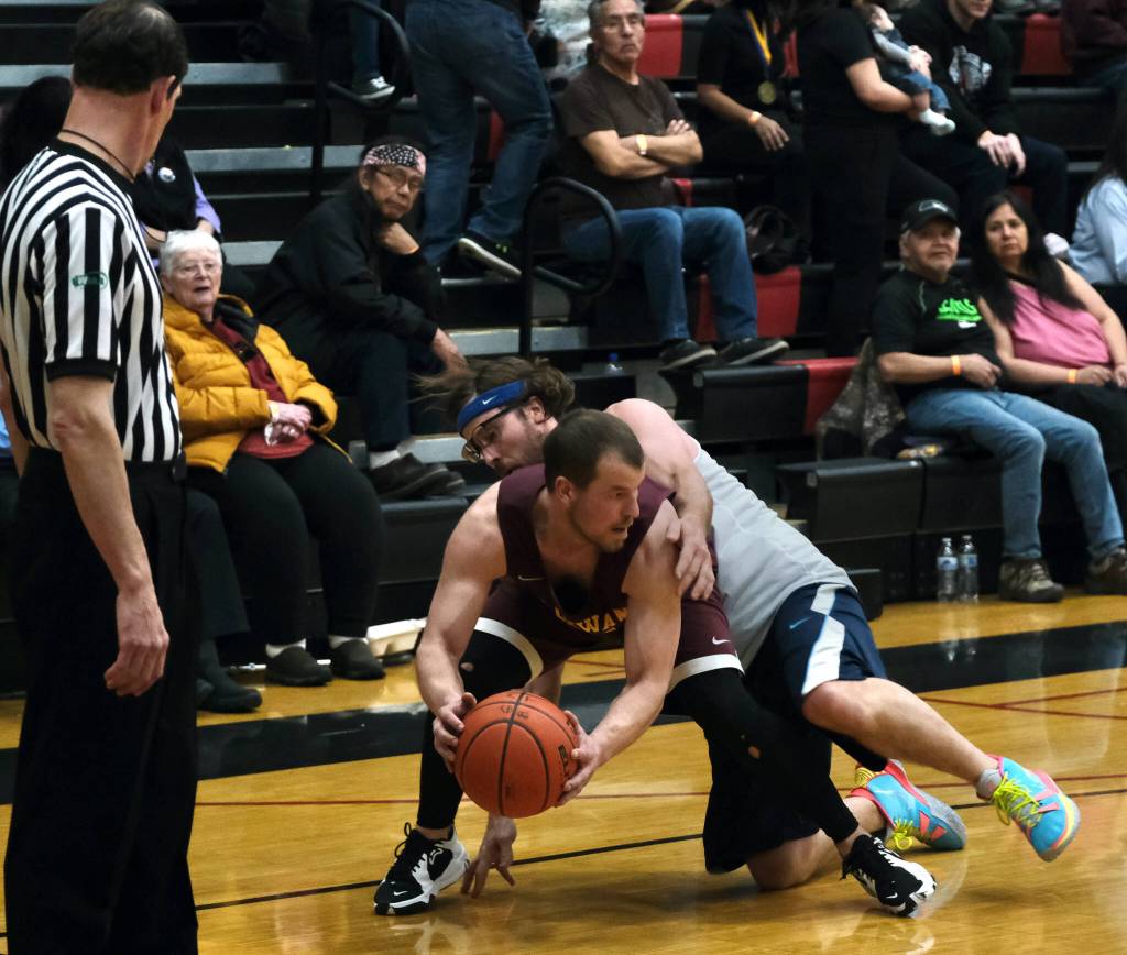 Klukwans Bryan Combs is fouled by Filcoms Adam Brown during the C Bracket Championship game of the Gold Medal Basketball Tournament, Saturday, March 25, at Juneau-Douglas High School: Yadaa.at Kalé. (Klas Stolpe/For the Juneau Empire)
