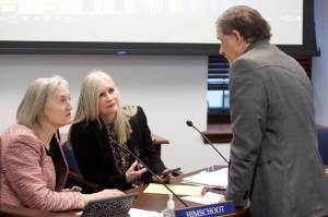 Mark Sabbatini / Juneau Empire 
State representatives Rebecca Himschoot, I-Sitka, left, and Andi Story, D-Juneau, discuss a proposal requiring school districts to maintain a public online checkbook with Rep. George Rauscher, R-Sutton, the bills sponsor, during a break in a House Education Committee meeting Wednesday. The two Southeast Alaska representatives expressed concerns about cyber security and small remote districts that do not have official websites.
