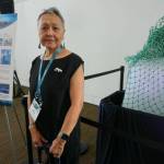 Vera Metcalf stands on Wednesday by a chunk of sea ice transported from Utqiagvik and displayed at the Arctic Encounter Symposium. The melting ice, which started at 310 pounds, symbolizes the rapid climate change that is weaking the Arctic ice pack, with profound implications for ecosystems, communties and cultures. (Photo by Yereth Rosen / Alaska Beacon)