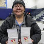 This March 28, 2023, photo shows JoAnn Kulukhon posing with two Alaska Heroism Medals presented posthumously to her uncles, Pvts. Luke and Leroy Kulukhon, during a ceremony in Gambell, Alaska. Sixteen Alaska National Guard members were honored for helping rescue the 11 crewmembers of a Navy plane that was shot down in 1955 by Soviet jet fighters and crash-landed about 8 miles from Gambell, on St. Lawrence Island, and 15 medals were presented posthumously. (AP Photo / Mark Thiessen)