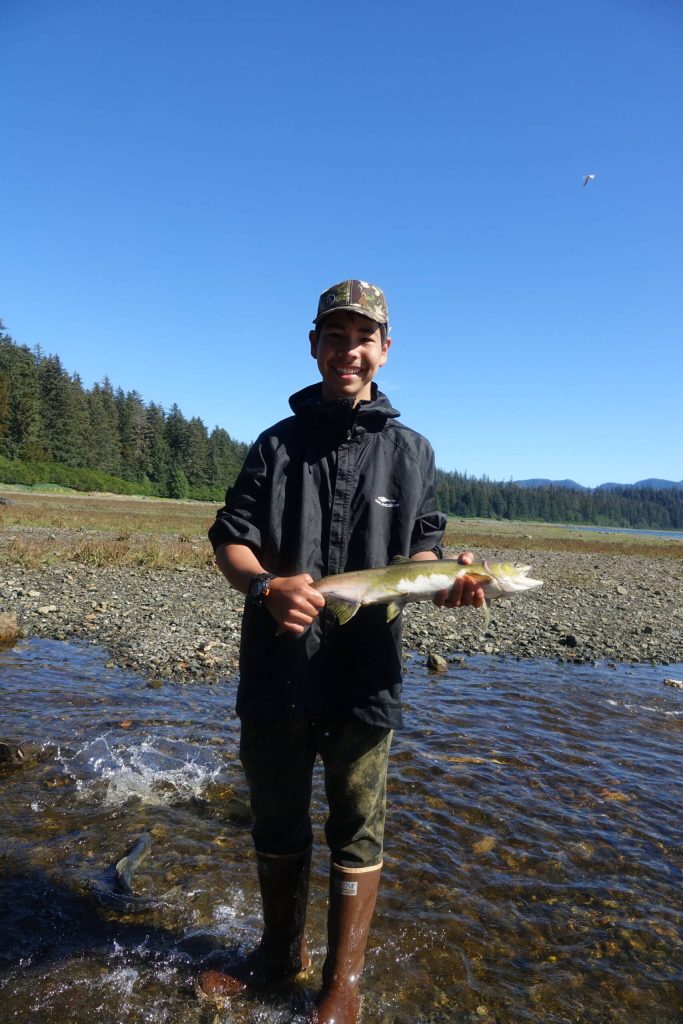 Beebuks Kookesh stands with a salmon he caught with his hands in a stream on Admiralty Island. He released it back into the water. (Courtesy Photo / Mary Catharine Martin)