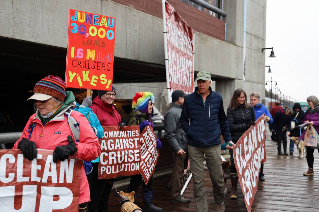 Juneau residents hold signs in advocacy of more environmental regulation of the cruise industry as passengers unboard the Norwegian Bliss Monday afternoon. (Clarise Larson / Juneau Epire)