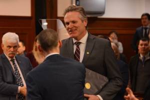 Alaska Gov. Mike Dunleavy shakes the hands of state legislators as he prepares to deliver the 2023 State of the State address to the Alaska Legislature on Jan. 23, 2023, in Juneau. (James Brooks/Alaska Beacon)
