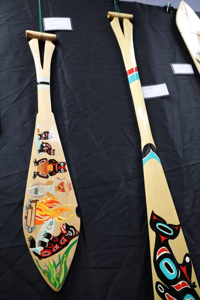 Two paddles, titled Invited the Bear (left) and Ocean Mother (right) made by University of Alaska Southeast alumni Diane Stambaugh, of Sweden, were two of the many works featured in a recent art gallery hosted Friday evening at UAS that showcased students work from the UAS Northwest Coast Art program. (Clarise Larson / Juneau Empire)