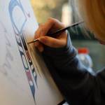 University of Alaska Southeast freshman Micheal Bethel paints a piece titled Parents on Friday while at an art gallery hosted Friday evening at UAS that showcased students work from the UAS Northwest Coast Art program. (Clarise Larson / Juneau Empire)
