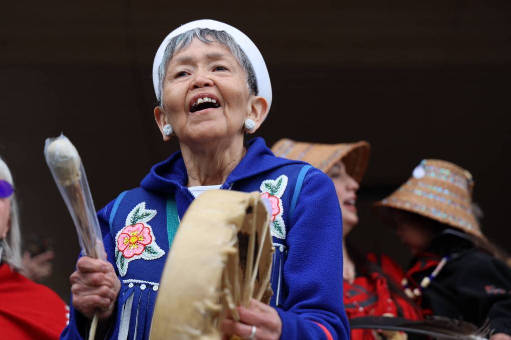 Sharon Lee drums to a song during the procession of the dedication ceremony of the Kootéeyaa Deiyí, Totem Pole Trail, held Saturday in downtown Juneau at Heritage Plaza. (Clarise Larson / Juneau Empire)