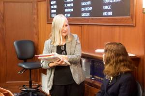 Rep. Andi Story, a Juneau Democrat, talks with a guest page on the House floor Wednesday morning. Story, a member of the House Education Committee, was among the members in the minority who expressed concern a bill giving teachers end-of-year bonuses will be used by House leaders to avoid a larger and more general increase to public school funding this session. (Mark Sabbatini / Juneau Empire)