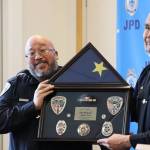 JPD Officer Kevin Fermin stands with Chief Ed Mercer while being presented with Fermins shadowbox, which is given to every officer at their retirement ceremony. (Jonson Kuhn / Juneau Empire)