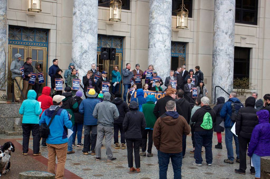 About 70 people, including 20 state lawmakers, gather in front of the Alaska State Capitol for a rally supporting a boost to public employee pensions on Tuesday evening. (Mark Sabbatini / Juneau Empire)