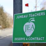 A car drives past a Juneau Education Association sign posted next to the North Douglas Highway Thursday morning. On Tuesday members voted to accept a three-year contract agreement with Juneau School District. (Clarise Larson / Juneau Empire)