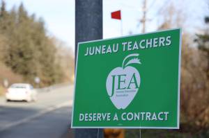 A car drives past a Juneau Education Association sign posted next to the North Douglas Highway Thursday morning. On Tuesday members voted to accept a three-year contract agreement with Juneau School District. (Clarise Larson / Juneau Empire)