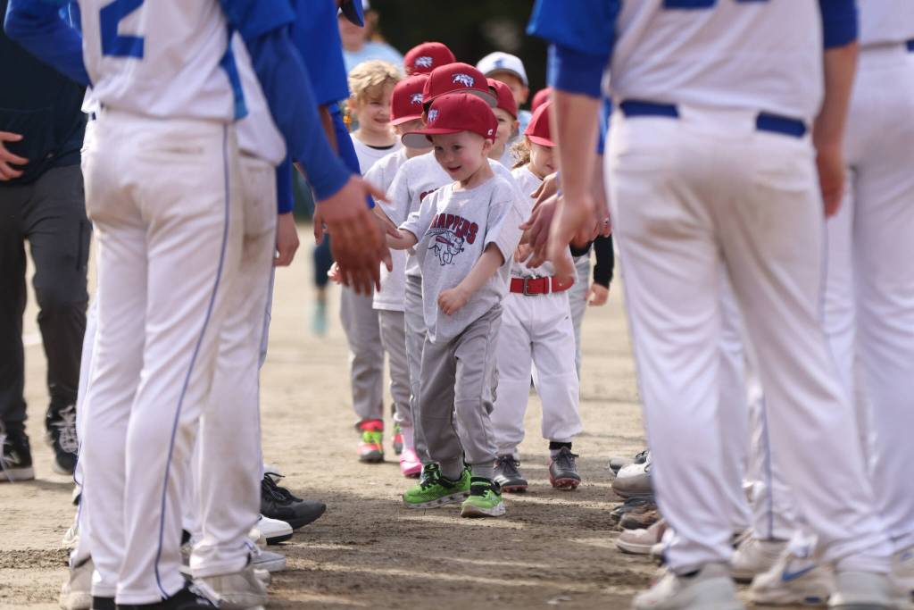 The Scrappers led by Ayden Thibodeau in front make their way through a line of Thunder Mountain High School baseball players on Gastineau Channel Little Leagues opening day. Forty teams took part in festivities held Saturday at Adair-Kennedy Memorial Park. (Ben Hohenstatt / Juneau Empire)