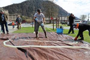 Sven Haakanson Jr. (center) helps unwind the small intestine of a Kodiak brown bear with the help of Peter Otsea (right) while Haakanson leads a bear gut processing workshop Saturday afternoon at the Alaska State Museum. (Clarise Larson / Juneau Empire)