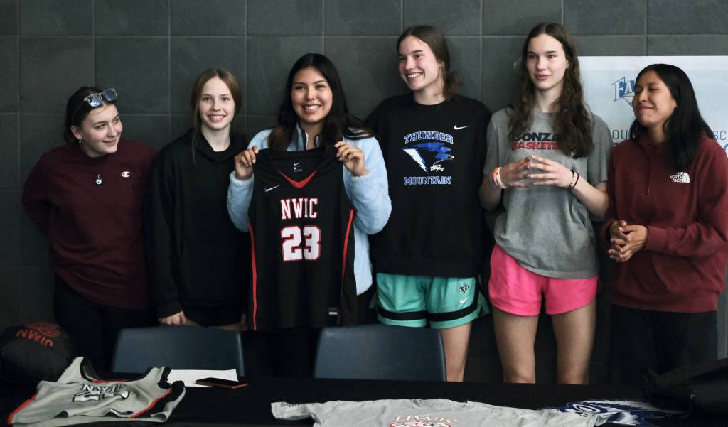 Thunder Mountain High School senior Kiara Kookesh, joined by teammates, holds a Northwest Indian College jersey after signing to play college basketball on Monday. Standing with her (from left to right) are Raynona Fraker, Bergen Erickson, Kookesh, Cailynn Baxter, Kerra Baxter and Emma Johnson. (Klas Stolpe / Juneau Empire)