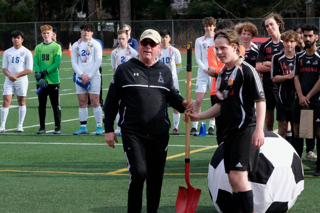 Juneau-Douglas High School: Yadaa.at Kalé coach Gary Lehnhart receives a shovel - for off season gardening - from senior Micah Brown during the Crimson Bears senior night celebration, Tuesday, at Adair Kennedy Field. (Klas Stolpe / Juneau Empire)