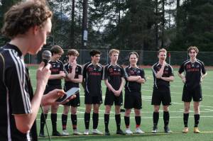 Juneau-Douglas High School: Yadaa.at Kalé  freshman Jesper Bennetsen (18) speaks about his senior brother Tayten Bennetsen (20), far right, during the JDHS boys final home game at Adair Kennedy pitch Tuesday. Seniors Jack Schwarting, Kean Buss (5), Gabe Cheng (21), Will Robinson (12), Micah Brown (23), Tommy Pearson (13) and T. Bennetsen listen. (Klas Stolpe / Juneau Empire).