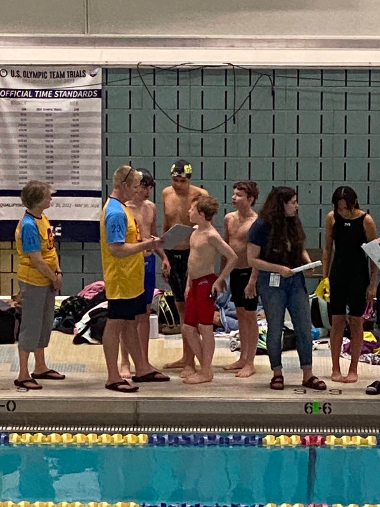 Glacier Swim Club swimmers Liam Kiessling, Sam Pallenberg, Andrew Sanders and Josh Edwards speaking to head coach Scott Griffith after the at the boys ages 13-14 relay race at this years Alaska Swimming State Championship in Anchorage. (Courtesy Photo / Savona Kiessling)