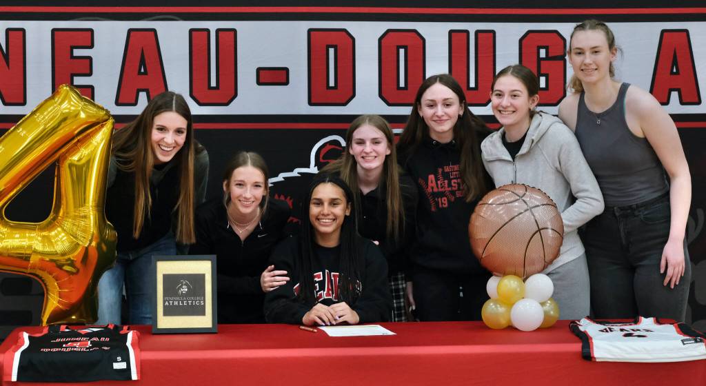 JDHS teammates pose with Kiyara Miller on Wednesday after she signed to play basketball at Peninsula College. From left: Mila Hargrave, Rayna Tuckwood, Miller, Tatum Billings, Chloe Casperson, Carlynn Casperson and Ashley Laudert. (Klas Stolpe / Juneau Empire)