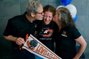 Mackenzie Olver is kissed by parents Barry and Stacy after signing a national letter of intent on Thursday in the Thunder Mountain commons, to play soccer and study at Lewis & Clark College in Portland, Oregon. (Klas Stolpe / Juneau Empire)