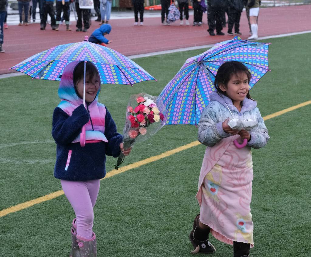 Bristol Refuerzo, 5, and Catherine Refuerzo, 6, bring flowers to TMHS senior Kylie Morris during the Lady Falcons senior ceremony on Friday. (Klas STolpe / Juneau Empire)