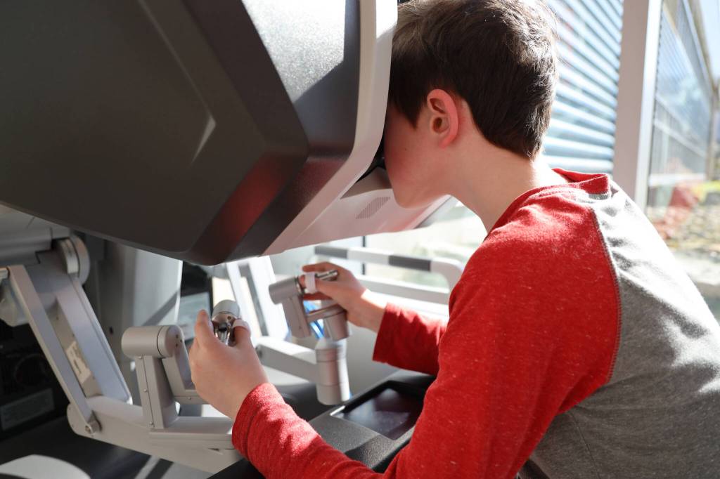 Eugene Rehfield, 10, controls the Da Vinci Xi Robotic Surgery System as he attempts to unwrap a Starburst while attending the open house celebration of the machine at the Bartlett Regional Hospital lobby Monday evening. (Clarise Larson / Juneau Empire)