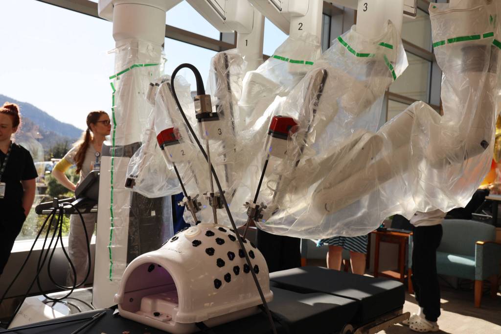 Residents and Bartlett Regional Hospital officials surround the Da Vinci Xi Robotic Surgery System on display at the hospitals lobby during an open house even for the machine Monday evening. (Clarise Larson / Juneau Empire)
