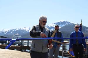 City and Borough of Juneau Docks and Harbors Board Vice Chairman Jim Becker cuts a ribbon Monday afternoon stretched across the Seawalk downtown in celebration of the citys completion of the Docks and Harbors Marine Deckover Project. (Clarise Larson / Juneau Empire)