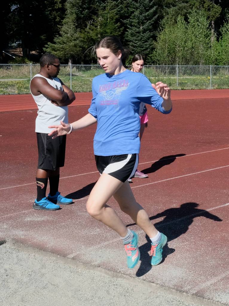 Thunder Mountain sophomore Kerra Baxter runs through a jump as Falcons coach Dwayne Duskin and sister Cailynn Baxter check her mark during Falcons track practice Wednesday. (Klas Stolpe / Juneau Empire)