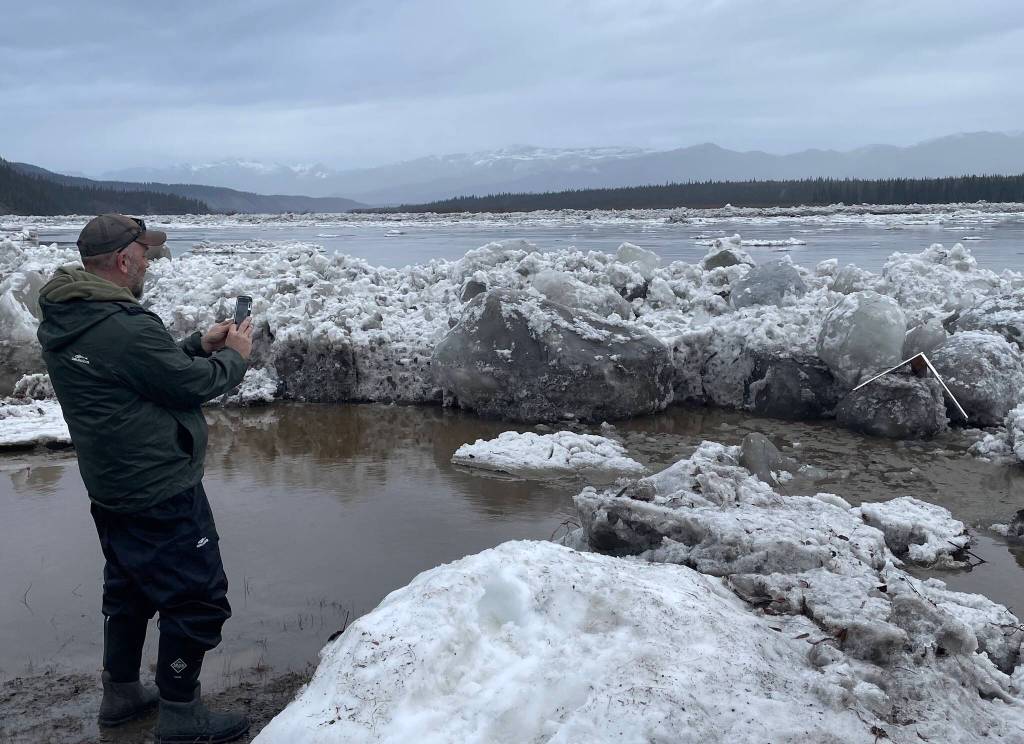 2. Ryan Becker, a teacher at the Eagle school, takes a photo of the toppled Front/Lincoln Street sign after Yukon River ice overtopped the town’s seawall on the morning of May 13, 2023. Photo by Ned Rozell.