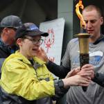 Athlete Tammy Birch carries the torch with help from Branden Horst during the Alaska Law Enforcement Torch Run at Twin Lakes Park Saturday morning. (Clarise Larson / Juneau Empire)