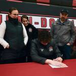 Juneau-Douglas High School: Yadaa.at Kalé Crimson Bears center Orion Dybdahl signs a letter of intent Monday to play basketball at Centralia College as brother Eli Dybdahl, mother Sarah Dybdahl, sister Michaela Demmert, father Travis Dybdahl and JDHS coach Robert Casperson look on Monday at the JDHS gym. (Klas Stolpe / Juneau Empire)